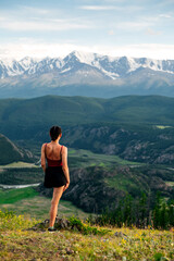 a girl in a red sweater enjoys a beautiful view of the mountains. Siberia. Altai