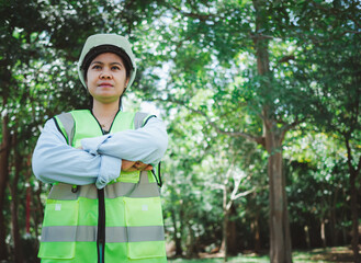 A female engineer wearing a hard hat stands with her arms crossed, Represents readiness to use digital technology to work with renewable energy, Sustainable business and zero-emissions industries.