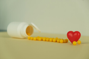 Yellow dragees poured out of a plastic jar on a white background close-up