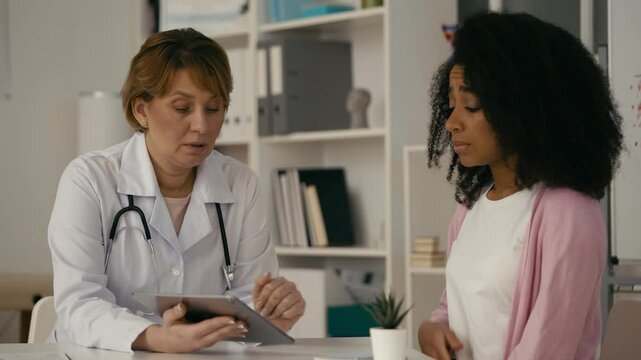 Doctor informing shocked young woman about bad diagnosis, comforting patient