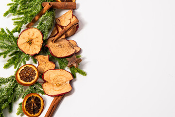 Dried oranges, cinnamon sticks and Christmas branches on white background, Christmas background with green branches, space for text, Christmas composition