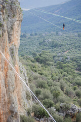 A tightrope walker walks along a cable stretched over a canyon.