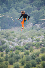 A tightrope walker walks along a cable stretched over a canyon.