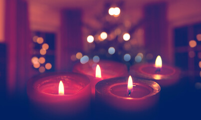 Four burning red Advent candles isolated on glowing Christmas tree background.
