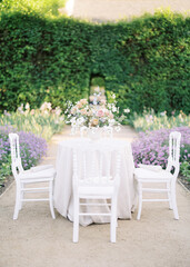 Fototapeta premium A beautifully decorated outdoor table with fresh flowers, ideal for garden parties, weddings, and elegant gatherings.