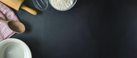 Fototapeta premium Escena para fondo de tarjeta. Fondo de pizarra negra. Elementos de cocina. Harina y uslero para hacer pan