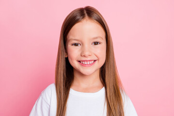 Portrait of charming cheerful little long-haired girl wearing white tshirt isolated over pink...