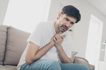 Man experiencing discomfort indoors, seeking relaxation at home on a bright day