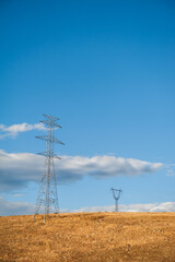 Powerline towers stand tall against a blue sky, symbolizing energy infrastructure