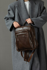 woman posing with a leather backpack wearing a warm gray coat