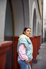 Woman in casual urban outfit standing by arched colonnade