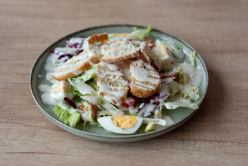 Close-up of hands with a plate of Caesar salad near the window in a cafe, during the day.