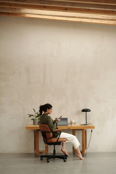 Architect sitting at desk by white wall and typing on laptop