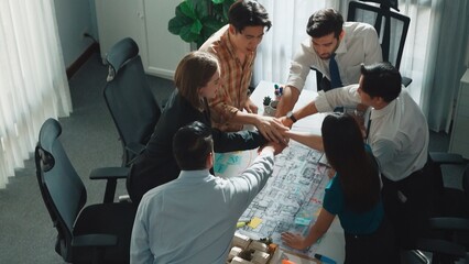 Top down aerial view of team putting hand together and cheering and encouraging team at meeting table with blueprint and architectural model. manager applause to successful project. Alimentation.