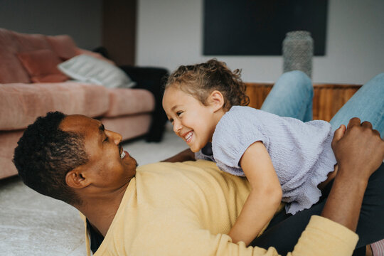 Happy father and daughter enjoying leisure time while lying down at home
