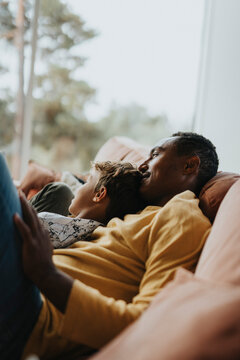 Father and son leaning on sofa in living room at home