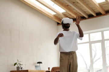 Architect wearing virtual reality headset, interacting with digital environment in modern living room