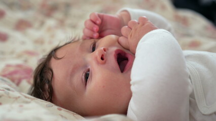 Close-up of baby resting on blanket with a calm expression, baby gazing softly, facial features...