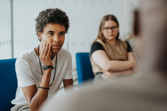 Teenage boy discussing with male counselor at high school