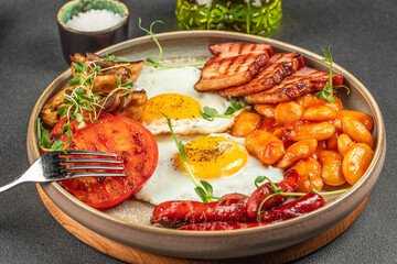 Traditional full English breakfast with fried eggs, sausages, beans, mushrooms, grilled tomatoes and bacon. top view