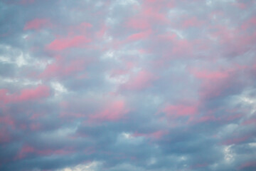 Evening dark clouds interspersed with the red color of the setting sun.