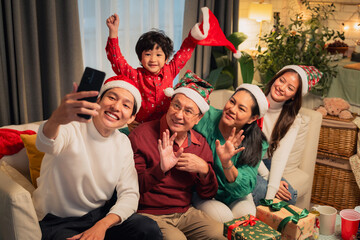 A joyful family celebrates Christmas together, taking selfie while wearing festive hats and surrounded by holiday decorations. atmosphere is filled with laughter and warmth