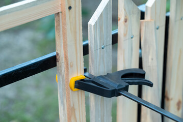 Building wooden fence DIY. Attaching wooden planks with same distance to make even fence using building bracket