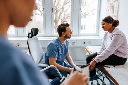 Young woman getting her leg examined by male medical expert in examination room