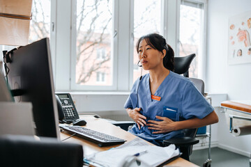 Female medical expert sitting on chair and doing online consultation on video call through computer at clinic