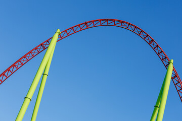 Colored metal roller coaster on a blue sky background on a sunny day.