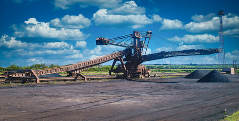 Loading iron ore conveyor machine on blue sky background in steel industry, UK