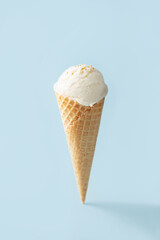 Vanilla ice cream ball in a waffle cone on a blue background