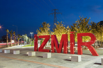 Red three-dimensional 3d letters containing the word IZMIR in the clear sky at evening time.