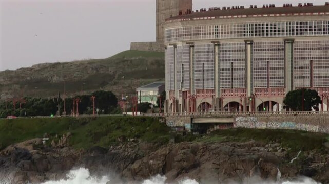 Pan of Tower of Hercules, lighthouse located in the Spanish city of A Coru&ntilde;a on a day with typical Galician weather with fog and rain with the sea hitting the rocks on which it is located