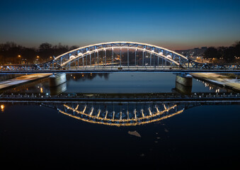 Fototapeta premium Pilsudski steel truss bridge over Vistula river in Krakow in the night, aerial view