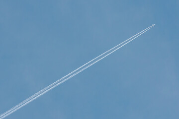 A jet airplane flying at high altitude, leaving a clean, straight contrail across the clear blue sky. The minimalist scene evokes freedom and simplicity in open airspace.