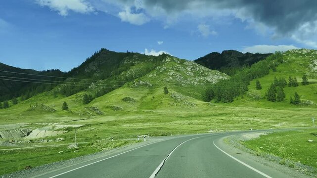 A road in a mountain valley among alpine meadows. 