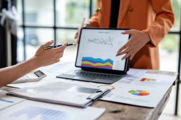 Businesswomen analyzing financial graphs on a digital tablet in a meeting
