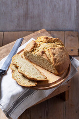 Homemade Irish soda bread cut into pieces and knife on wooden background.