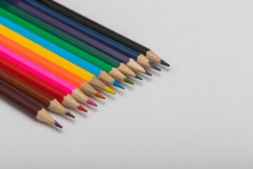 Colored crayons on a white background. The crayons are brown, black, yellow, orange, blue, purple