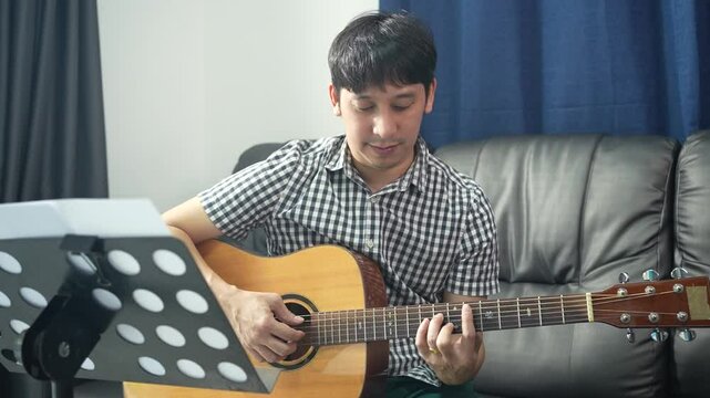 A middle-aged man was playing his favorite song on the guitar.