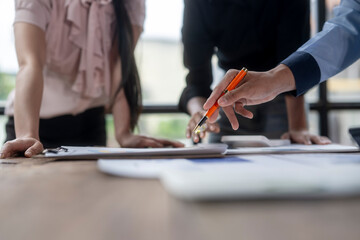 A man is pointing at a piece of paper with a pen