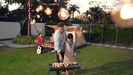 Family together in garden, father and daughter grill food for family member. Outdoor camping...
