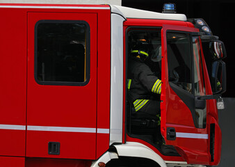 firefighter stepping out from red fire truck to handle city emergency situation with people in need...