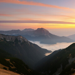 Obraz premium Landscape of green mountains with foggy valley mist between high peaks red to pink sky scenic sunset or sunrise