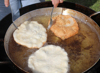 fritters frying in a big pot with hot oil at a country festival chef forks