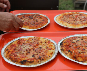 hand of a pizza maker who prepared margherita pizzas with tomato sauce and mozzarella cheese
