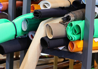 rolls of fabric and textiles on shelves in the shop ready for designers and tailors