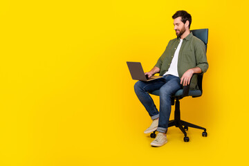 Full length portrait of nice young man sit chair laptop empty space wear shirt isolated on yellow color background