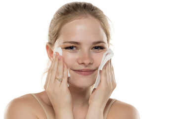 Portrait of a young smiling woman removing her make-up on a white studio background.